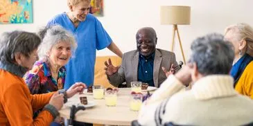 A multigenerational group gathered around a dining table in a warm home setting